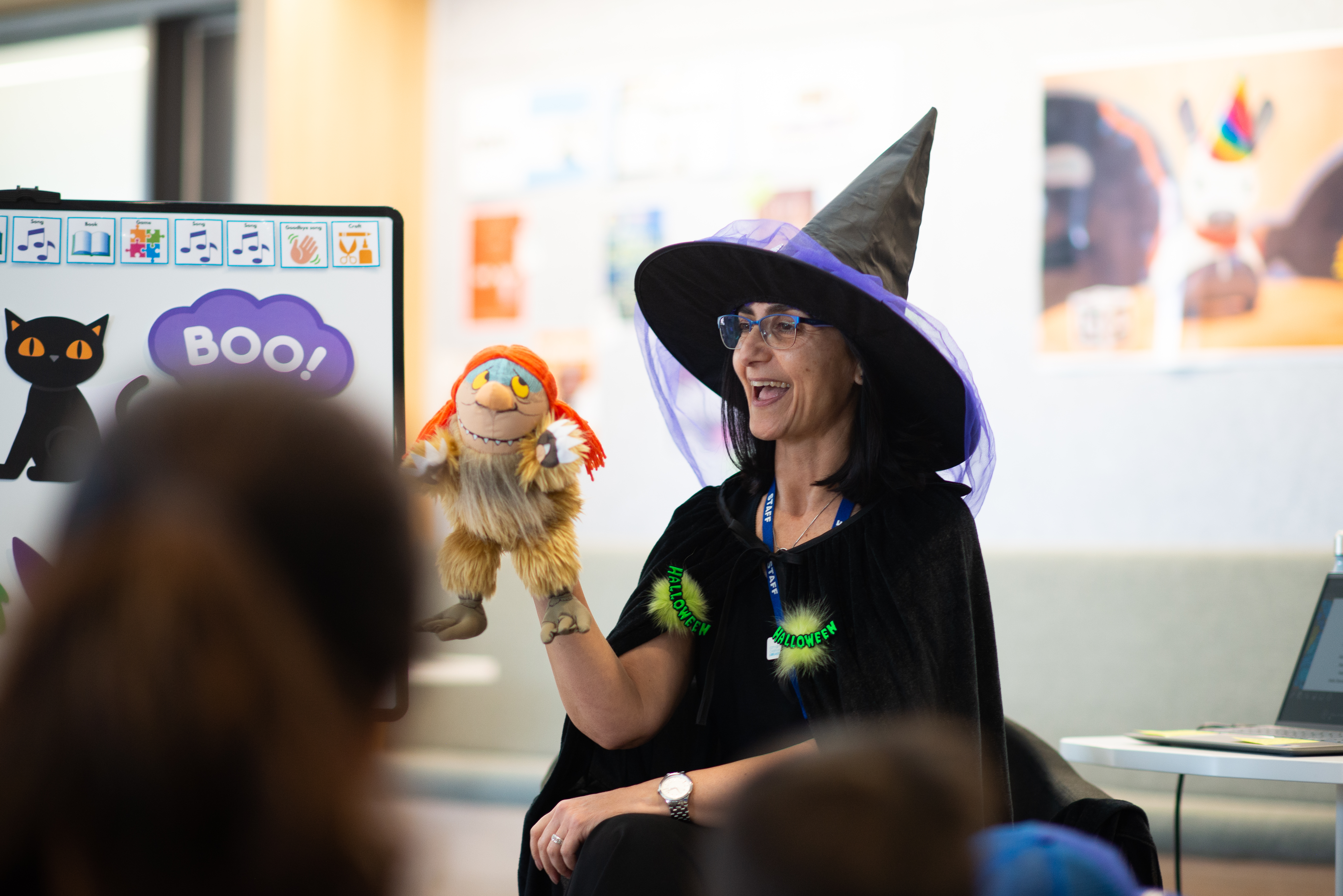 Librarian wearing witch costume telling a story with puppet