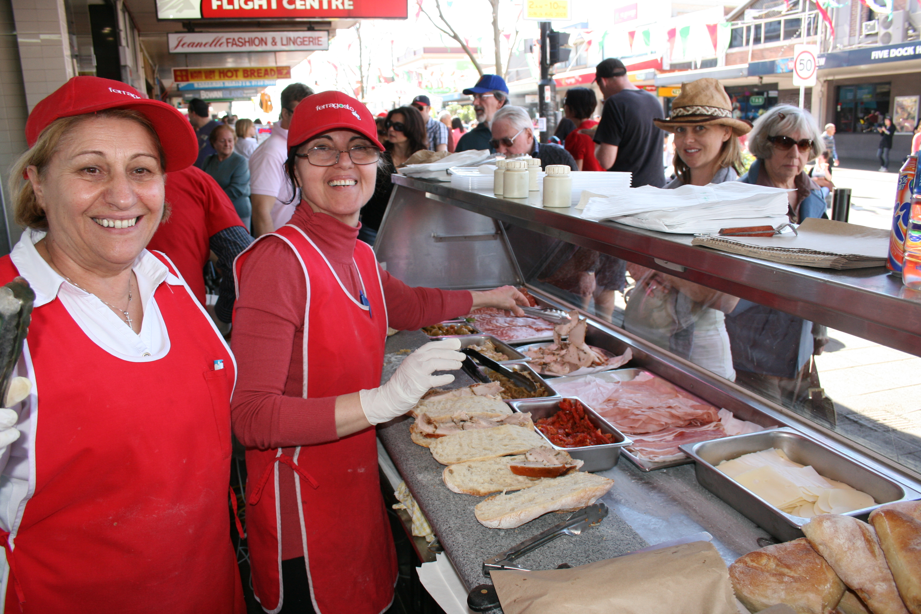 people smiling serving sandwhiches
