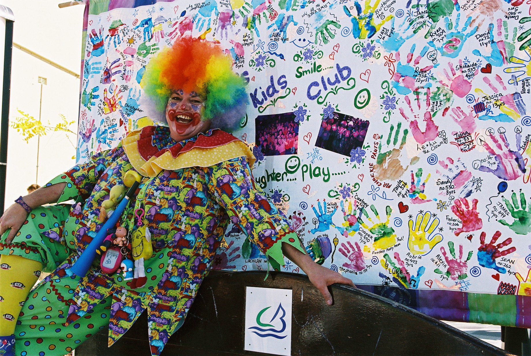 clown smiling in front of a board with kids club