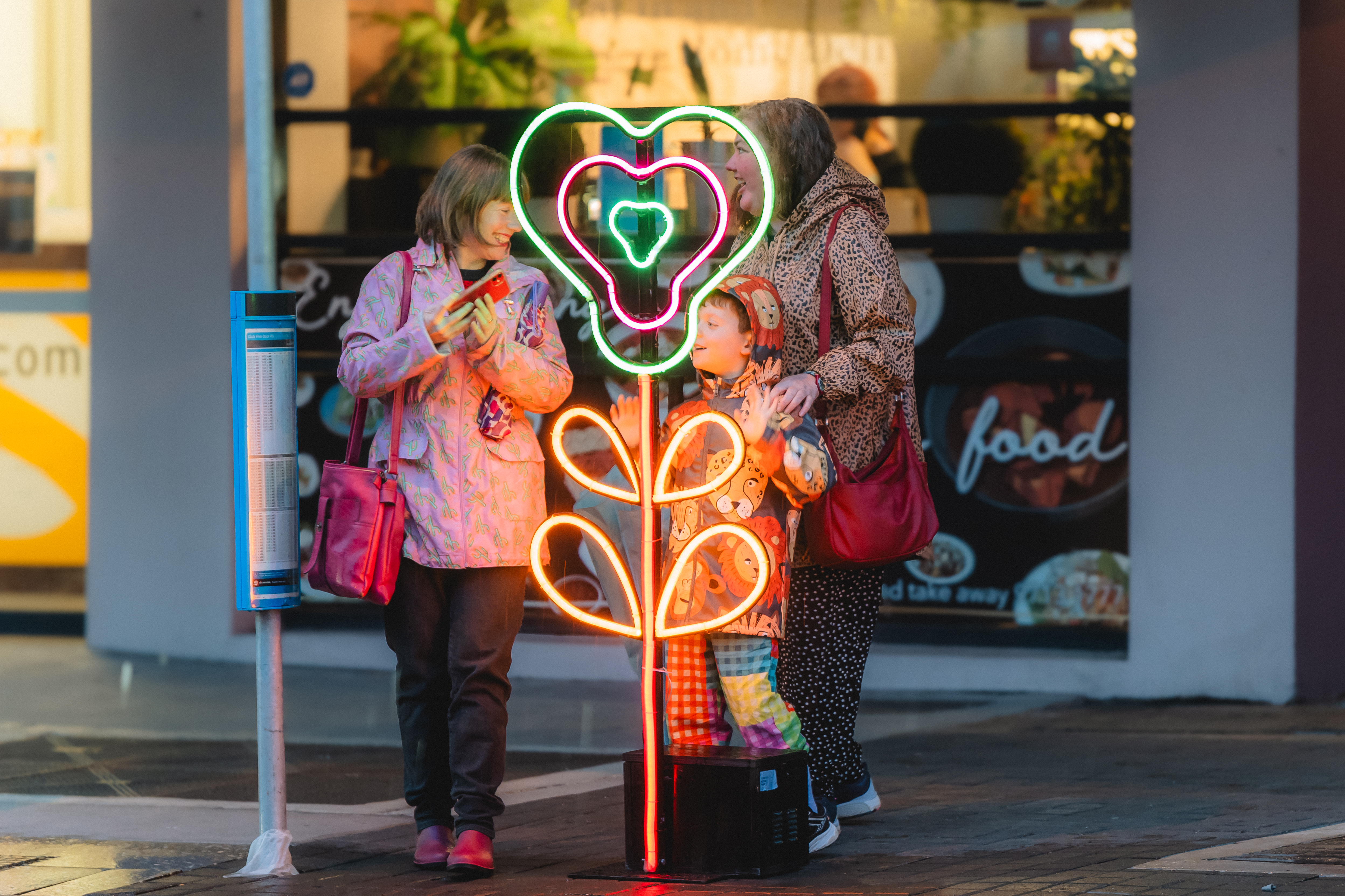 Family smiling behind neon light flower