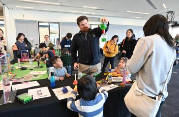 Scientist from Fizzics Education performing an experiment for local children who watch on