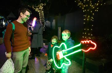 Young boy posing behind a neon guitar