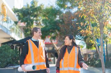 Two Council staff in orange vests laughing